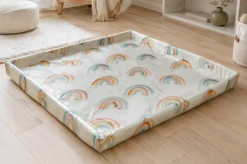 Tapis d’éveil pliable à motifs d’arcs-en-ciel, déployé au sol dans une pièce familiale lumineuse